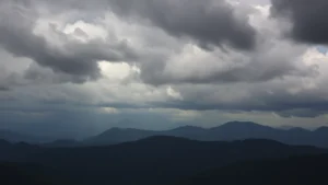 Dramatic storm clouds rolling over Blue Ridge Mountains near Asheville North Carolina, dark thunderheads building above forested peaks, moody atmospheric mountain landscape, cinematic weather photography