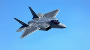 Modern stealth fighter jet in flight against clear blue sky, sleek angular design with matte gray finish, dynamic banking maneuver showing advanced aerodynamics and cutting-edge military aircraft engineering