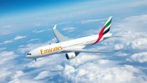 Modern Boeing 777 aircraft in Emirates livery cruising through clear blue skies above cloud formations, professional aviation photography, daylight, high altitude perspective