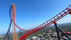 Falcon's Flight hypercoaster towering against blue sky, showing full track structure with dramatic angles and inversions, aerial perspective of theme park landscape below