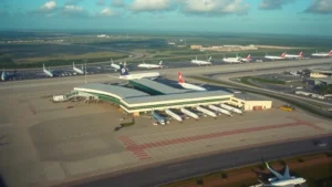 Aerial view of Orlando International Airport terminal with aircraft lined up at gates, sunny Florida landscape visible below, daytime photography