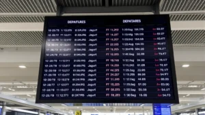 Modern airport departure board displaying multiple flights with LED display showing Philippine Airlines flight numbers, times, and status updates in Manila international airport terminal